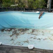 Drained above ground pool showing damaged vinyl liner